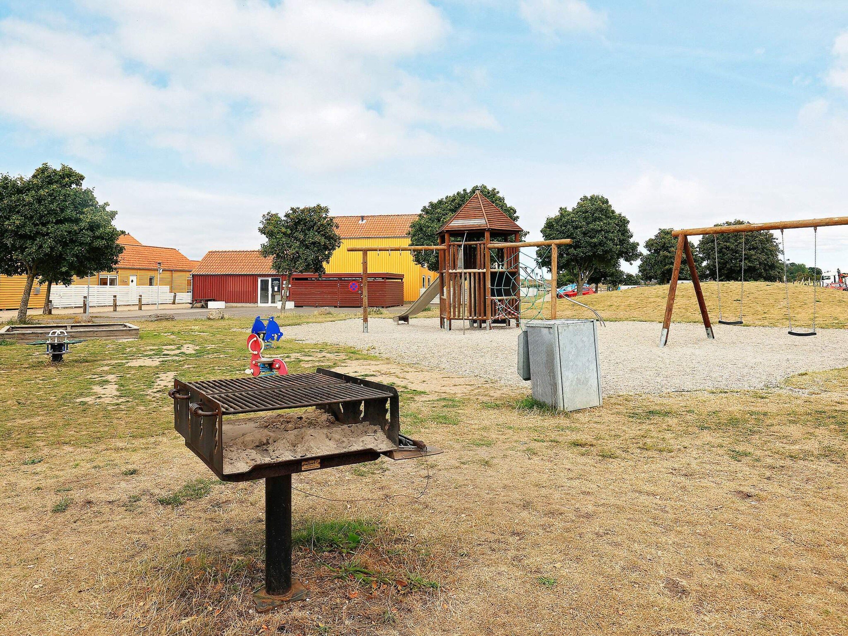 Un parc infantil amb un joc de cadira, una estructura per escalar i un edifici petit.