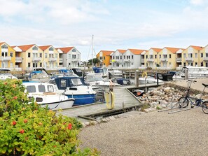 Eine Marina mit vertäuten Booten, einer Holzsteg und Reihenhäusern im Hintergrund.