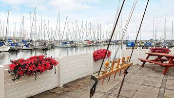 Un puerto deportivo con barcos amarrados, un banco de madera y flores rojas.