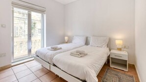 A bedroom with two beds, a window, and a nightstand with a lamp. - Marina VIEW APT SLPs 9 with private terrace & BBQ (Ta` Xbiex)