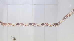 Un baño pequeño con azulejos, un inodoro, un desagüe y un borde decorativo.