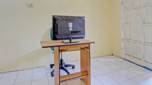 Un televisor sobre un soporte de madera en una habitación con piso de baldosas y una puerta blanca.