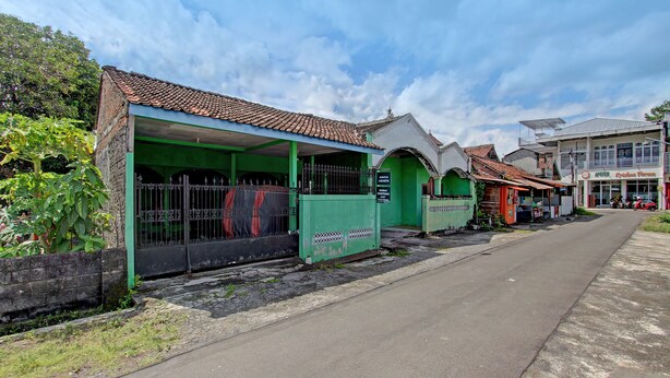 Una calle con edificios, incluyendo una estructura verde con zona cubierta y un letrero que dice 'APOTEK'.