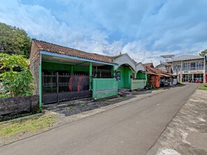 A street with buildings, including a green structure with a covered area and a sign that reads "APOTEK." - SPOT ON 91764 Griya Amarta Syariah (Banguntapan)