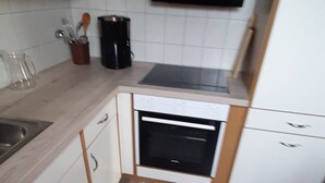 Ett kompakt kök med en inbyggd ugn, en kaffebryggare och en mikrovågsugn.