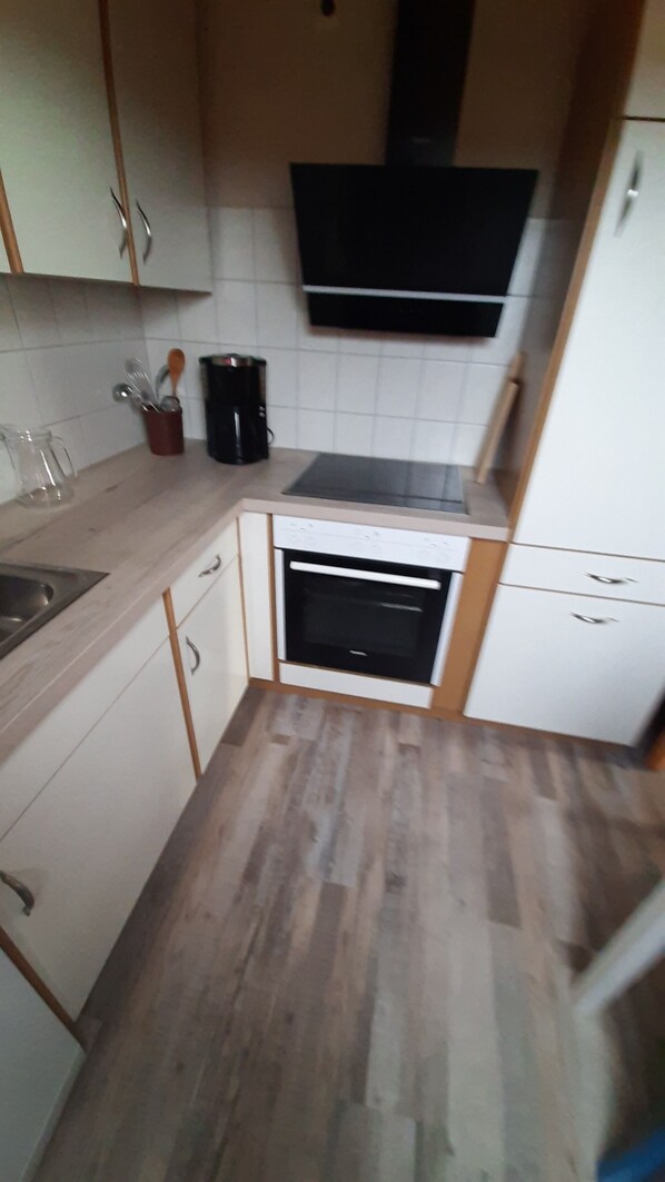 A compact kitchen with a built-in oven, a coffee maker, and a microwave.