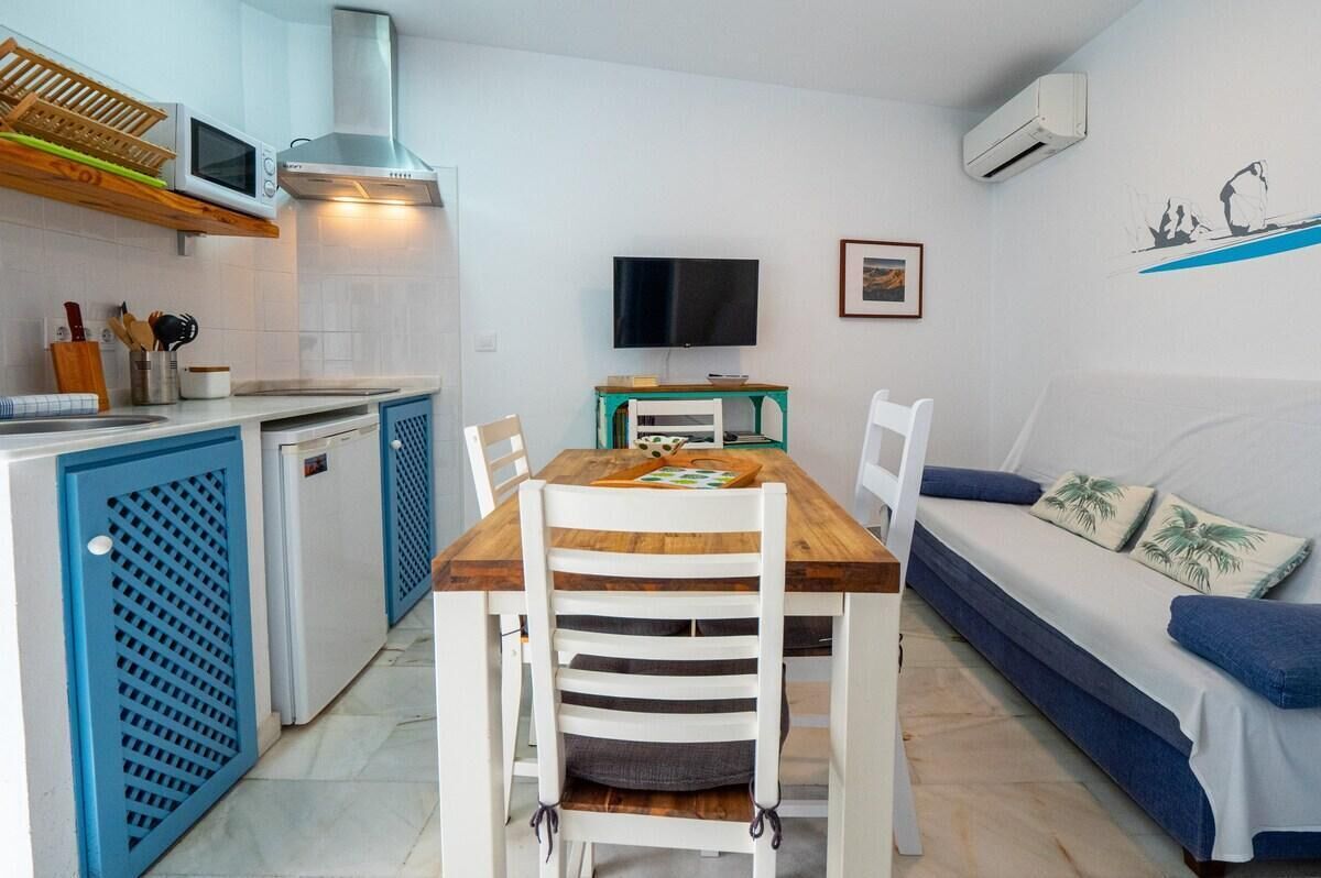 A compact kitchen with a dining area, a TV, and a sofa.
