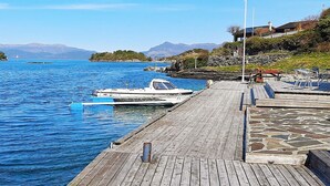 A wooden dock extending into calm blue waters with a boat docked at the end. - 5 Person Holiday Home in Sjernaroy (Stavanger)