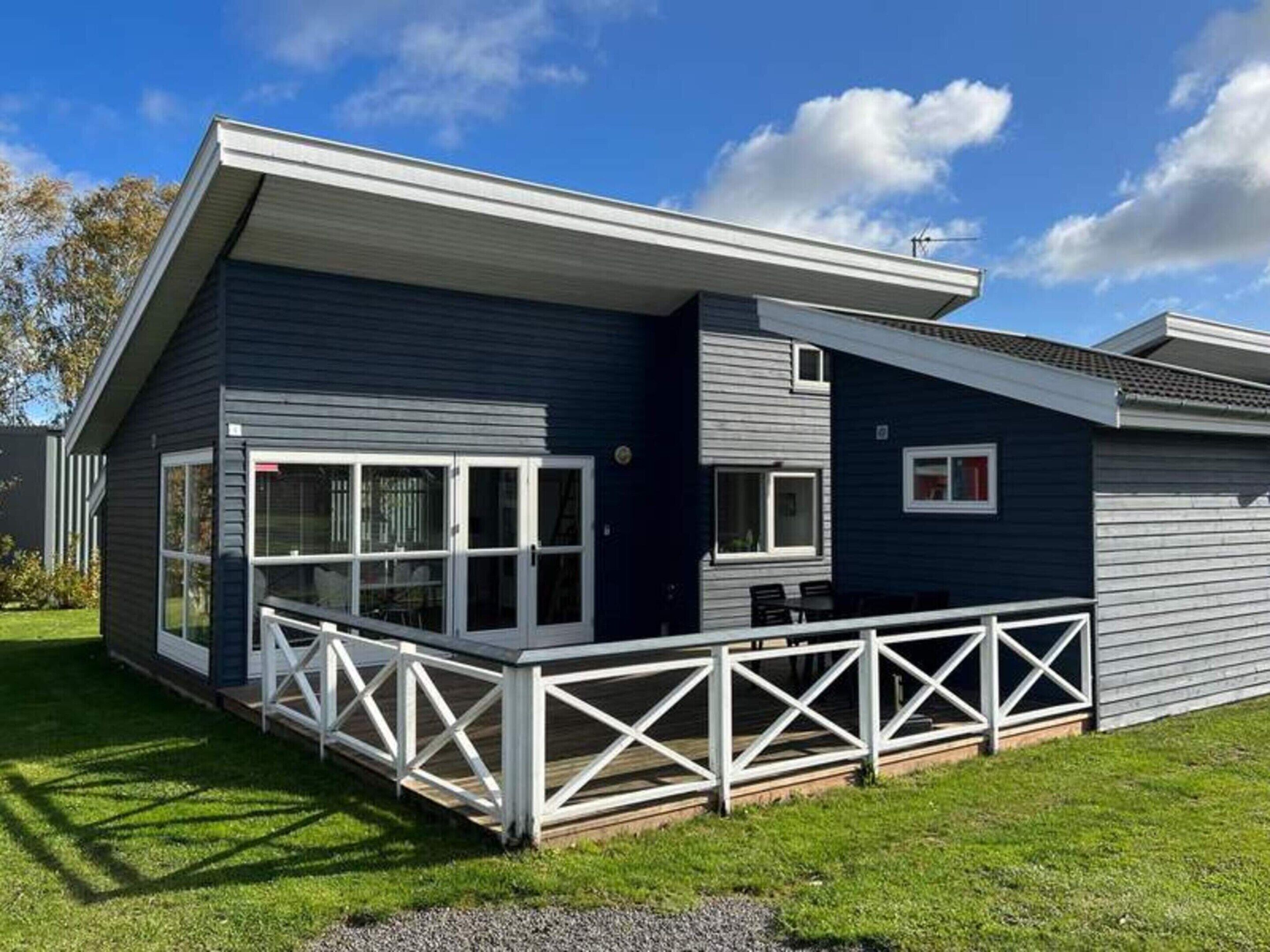 A modern two-story house with a covered patio and a fenced deck.