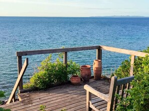 A wooden deck with terracotta pots and a bench overlooking a body of water. - 6 Person Holiday Home in Gilleleje (Gilleleje)