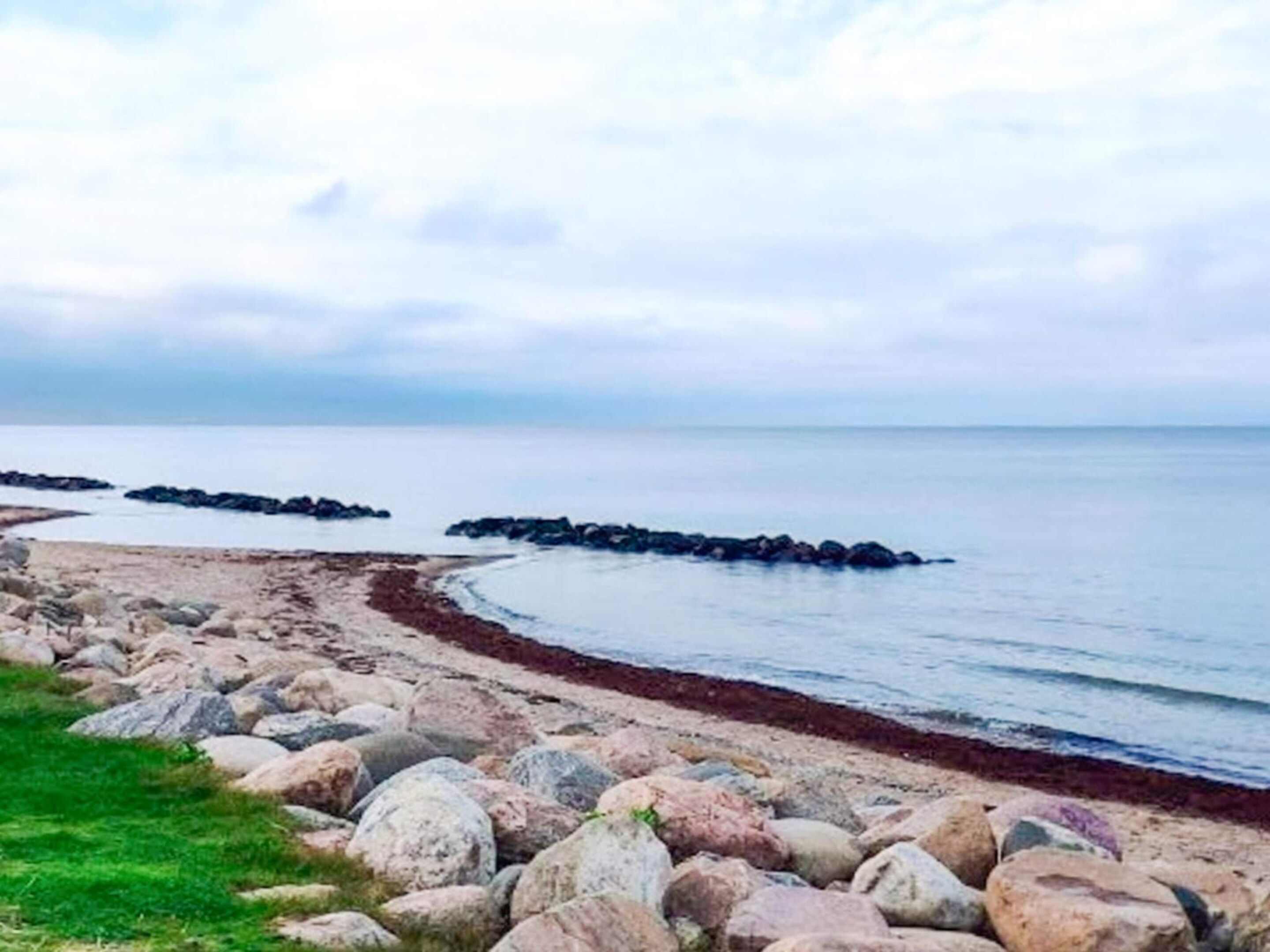Un paisaje costero con una costa rocosa, una zona cubierta de hierba y un mar tranquilo.