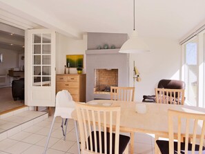 A dining area with a wooden table and chairs, a fireplace, and a view of the outdoors. - 6 Person Holiday Home in Gilleleje (Gilleleje)