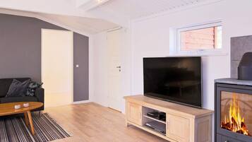 Una sala de estar moderna con un televisor de pantalla plana, un mueble de madera para entretenimiento, un sofá y una chimenea.