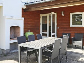 An outdoor patio with a table and chairs, a grill, and a brick fireplace. - 6 Person Holiday Home in Gilleleje (Gilleleje)