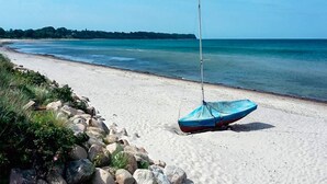 A beach with a sailboat on the sand, a rocky shoreline, and a clear view of the sea. - 6 Person Holiday Home in Gilleleje (Gilleleje)