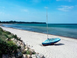 A beach with a sailboat on the sand, a rocky shoreline, and a clear view of the sea. - 6 Person Holiday Home in Gilleleje (Gilleleje)