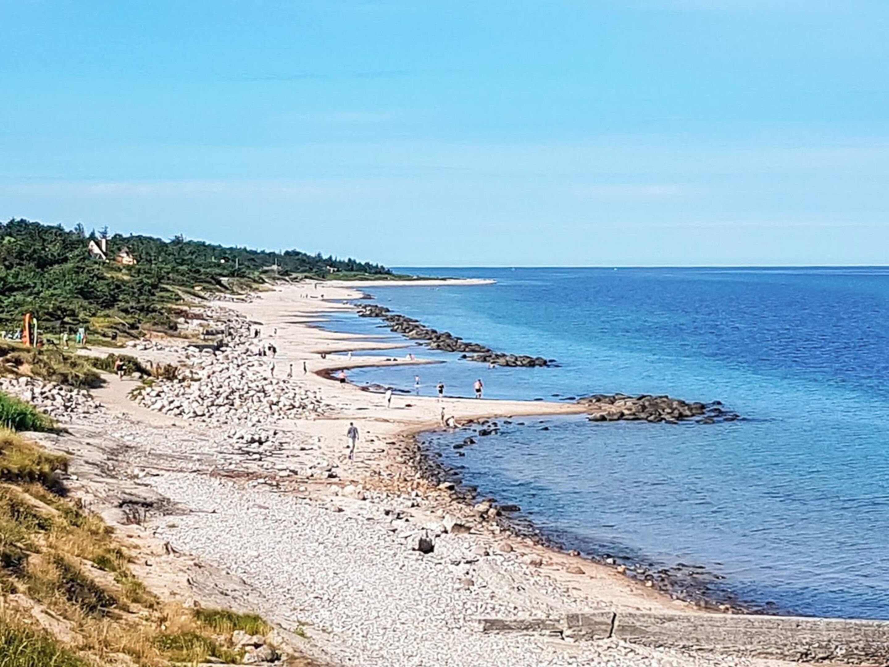 A coastal beach with rocky terrain and clear blue waters.