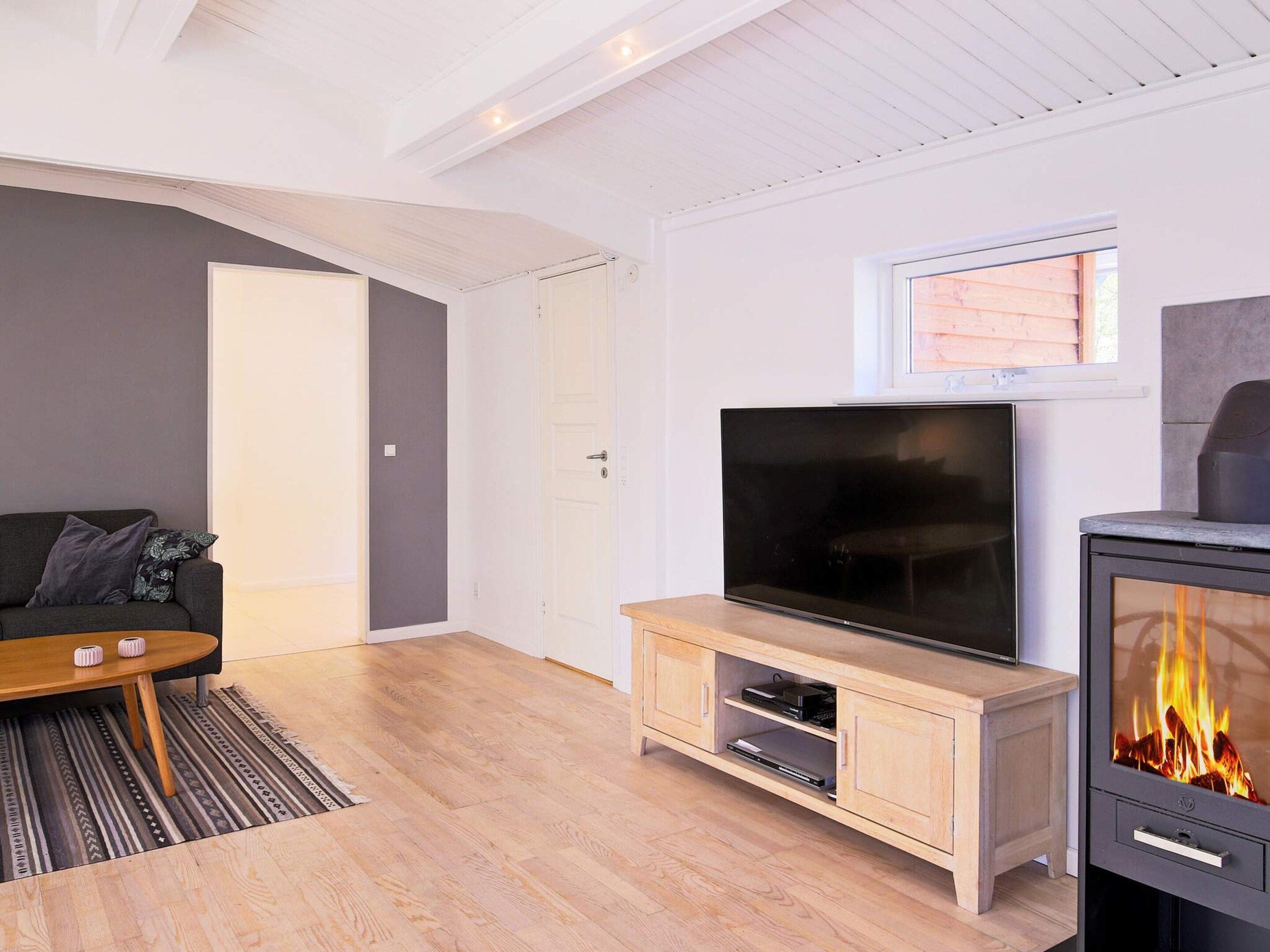 A modern living room with a flat-screen TV, a wooden entertainment unit, a sofa, and a fireplace.