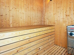 A sauna with wooden benches and a visible control panel.