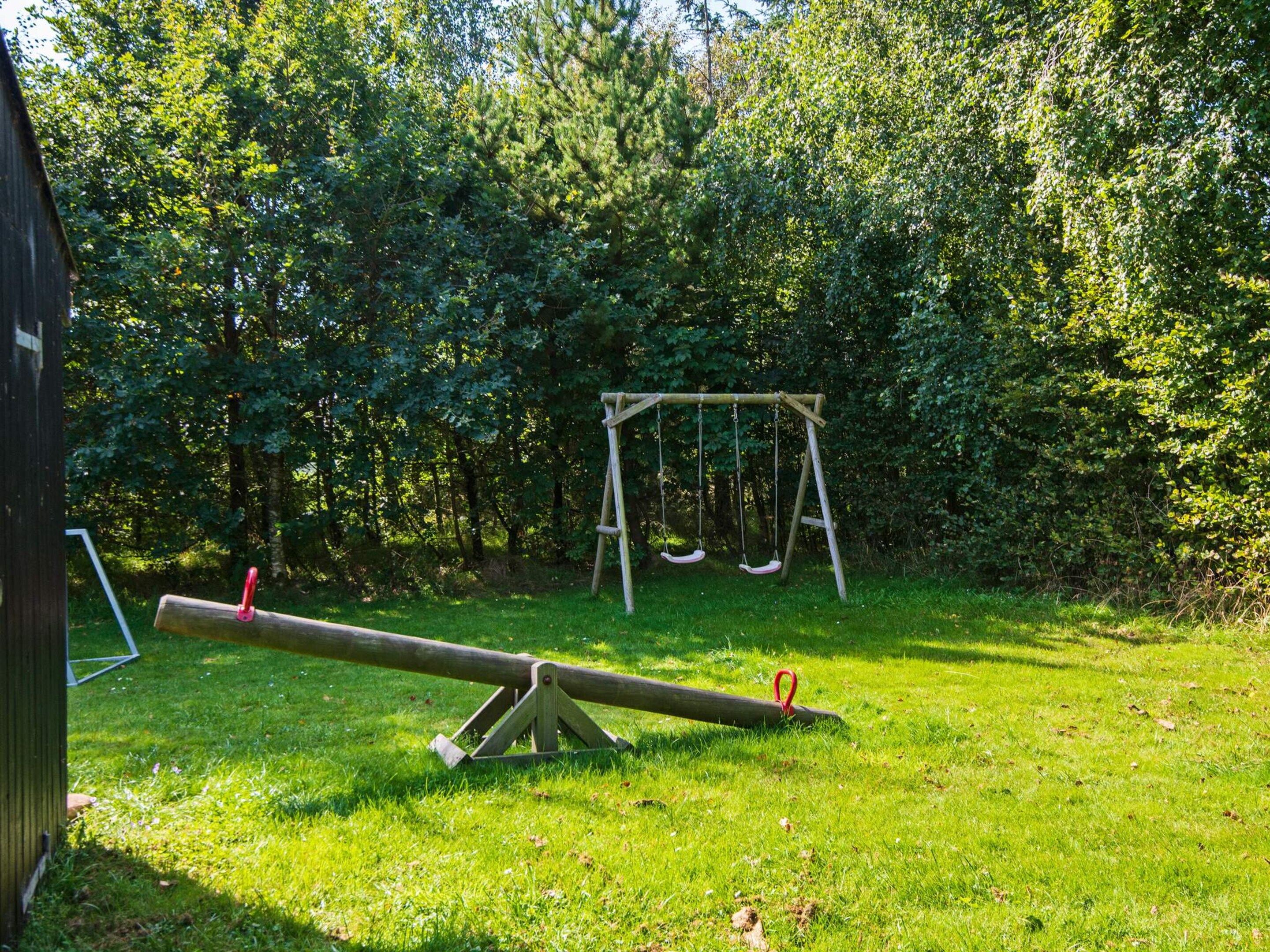 En gungbräda på en gräsyta med träd i bakgrunden.
