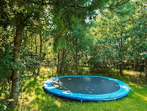 A trampoline surrounded by dense green foliage in a natural setting. - 4 Star Holiday Home in Ringkobing (Ringkobing)