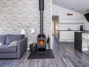 A modern living room with a stone wall, a sofa, a floor lamp, and a wood-burning stove.