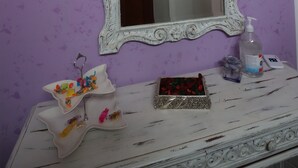 A bathroom with a purple wall, a white ornate mirror, and a white vanity with a decorative box and toiletries. - B&B stella polare Rieti (Rieti)