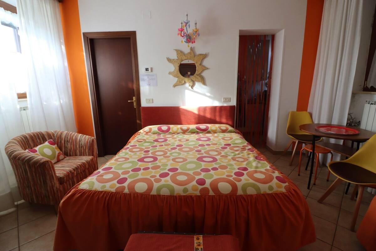 A hotel room with a bed, a chair, a table, and a wall decoration.