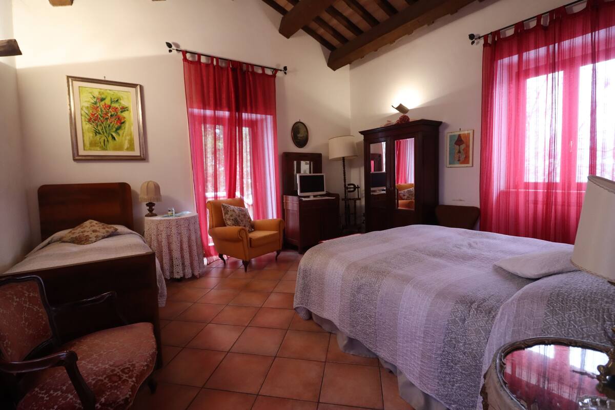 A bedroom with a bed, a chair, a small table, a lamp, and a cabinet.