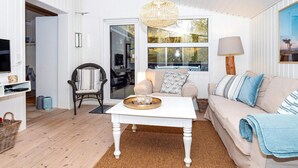 A cozy living room with a white sofa, a coffee table, and a wicker chair.