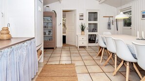 A modern kitchen with white cabinets, a dining area with a white table and chairs, and a kitchen island with a sink.