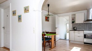 Ett modernt kök med vita skåp, en fläktkåpa i rostfritt stål och ett matbord i trä med tillhörande stolar.