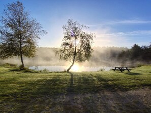 Una escena tranquila junto al lago, con una mesa de picnic y árboles.