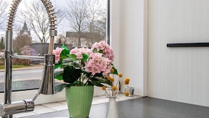 En diskho med en modern blandare, en grön vas med rosa blommor och en vit vas med gula blommor.