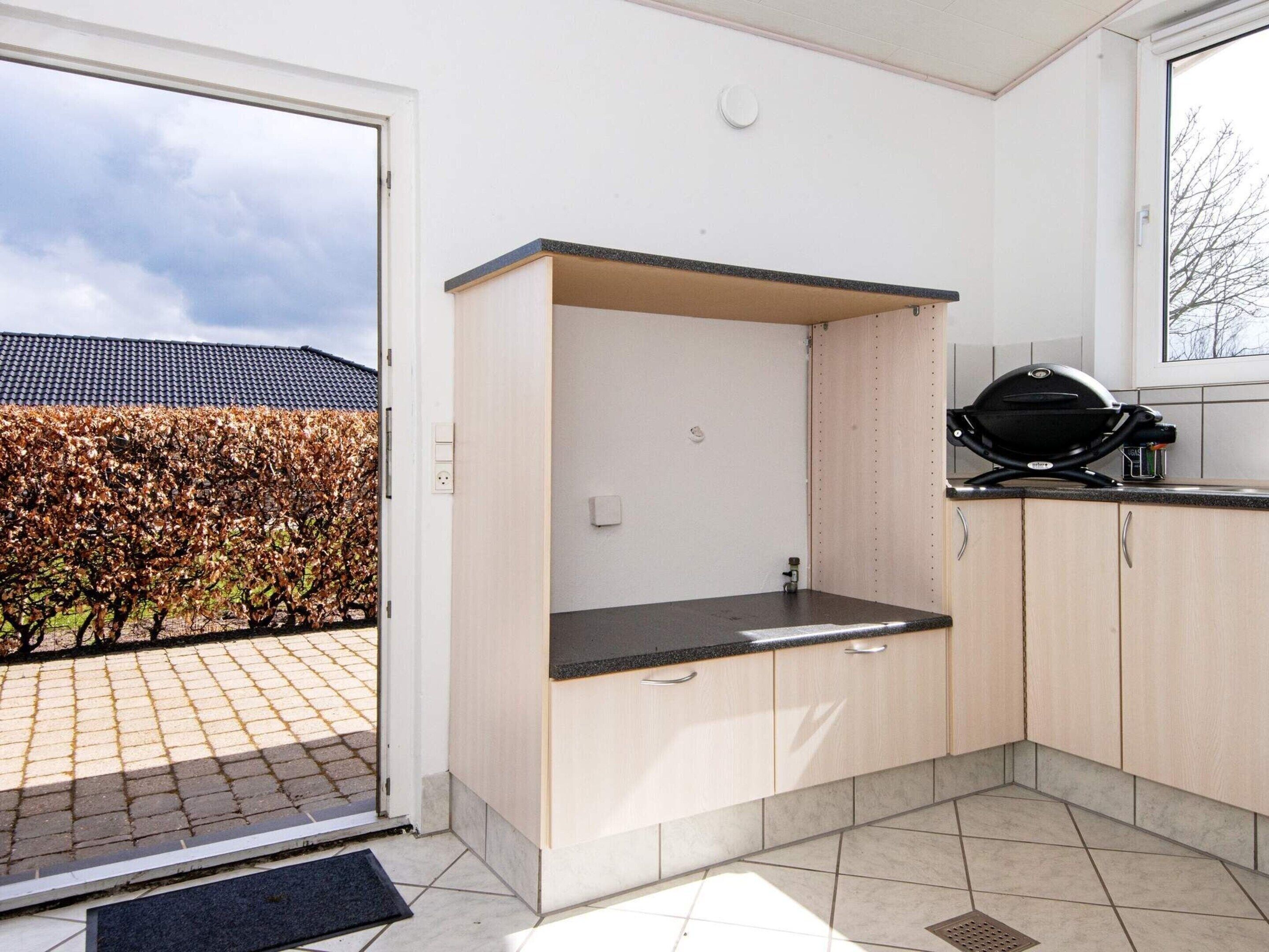 A compact kitchen with a built-in sink, wooden cabinets, and a grill on the countertop.
