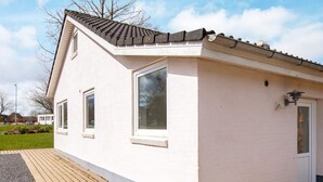 En liten, envåningsbyggnad med vit fasad och ett mörkt tak. Den har två fönster och en dörr, och framför byggnaden finns en stenlagd gångväg.