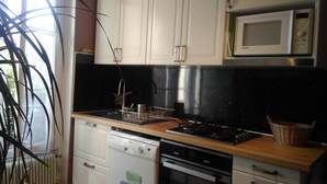 A kitchen with white cabinets, a black countertop, a microwave, a dishwasher, and a stove. - Paris 14th with kitchen 150m metro Glacière 30m2 Quiet (Paris)