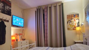 A bedroom with a bed, a TV on the wall, a lamp, and a poster. - Paris 14th with kitchen 150m metro Glacière 30m2 Quiet (Paris)