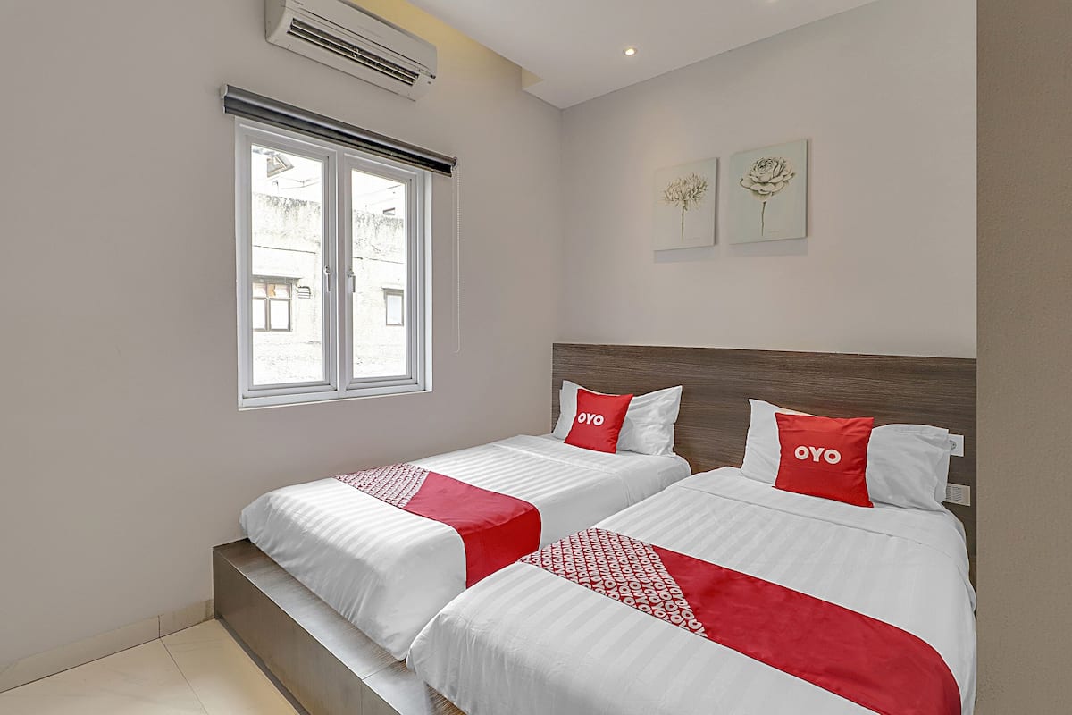 Une chambre d’hôtel avec deux lits, une fenêtre et un climatiseur fixé au mur.