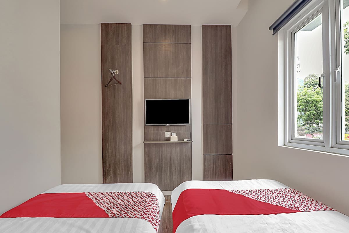 Une chambre avec deux lits, une télévision et une fenêtre.