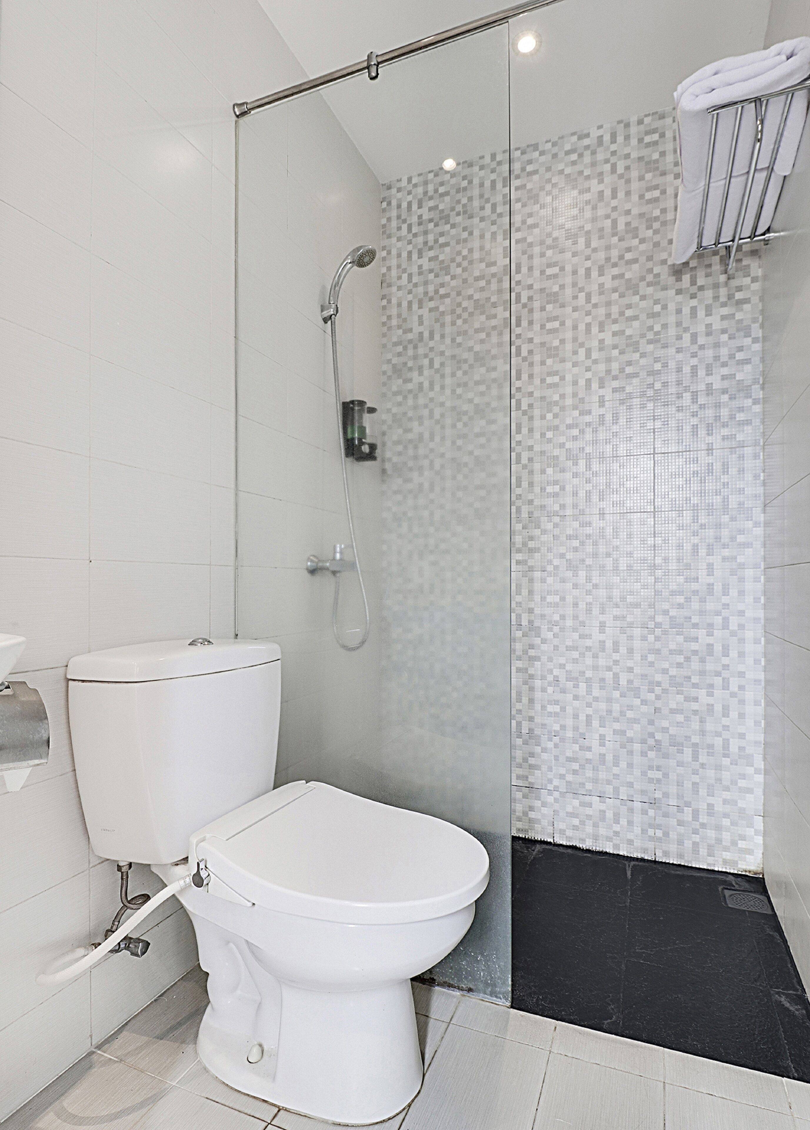 A modern bathroom with a toilet, a shower enclosure, and a tiled floor.