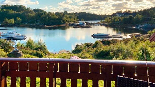 A lakeside view with boats, a wooden deck, and a forested shoreline. - 6 Person Holiday Home in Korssund (Fjaler)