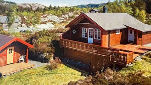 A wooden cabin with a deck, surrounded by natural landscape and mountains. - 6 Person Holiday Home in Korssund (Fjaler)