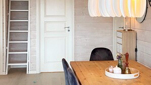 A wooden dining table with a white tray, a vase with flowers, and a candle. There is a black chair in front of the table. A white door with a handle is visible in the background. - 6 Person Holiday Home in Korssund (Fjaler)