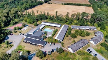 An aerial view of a property with multiple buildings, parking areas, and surrounding fields.