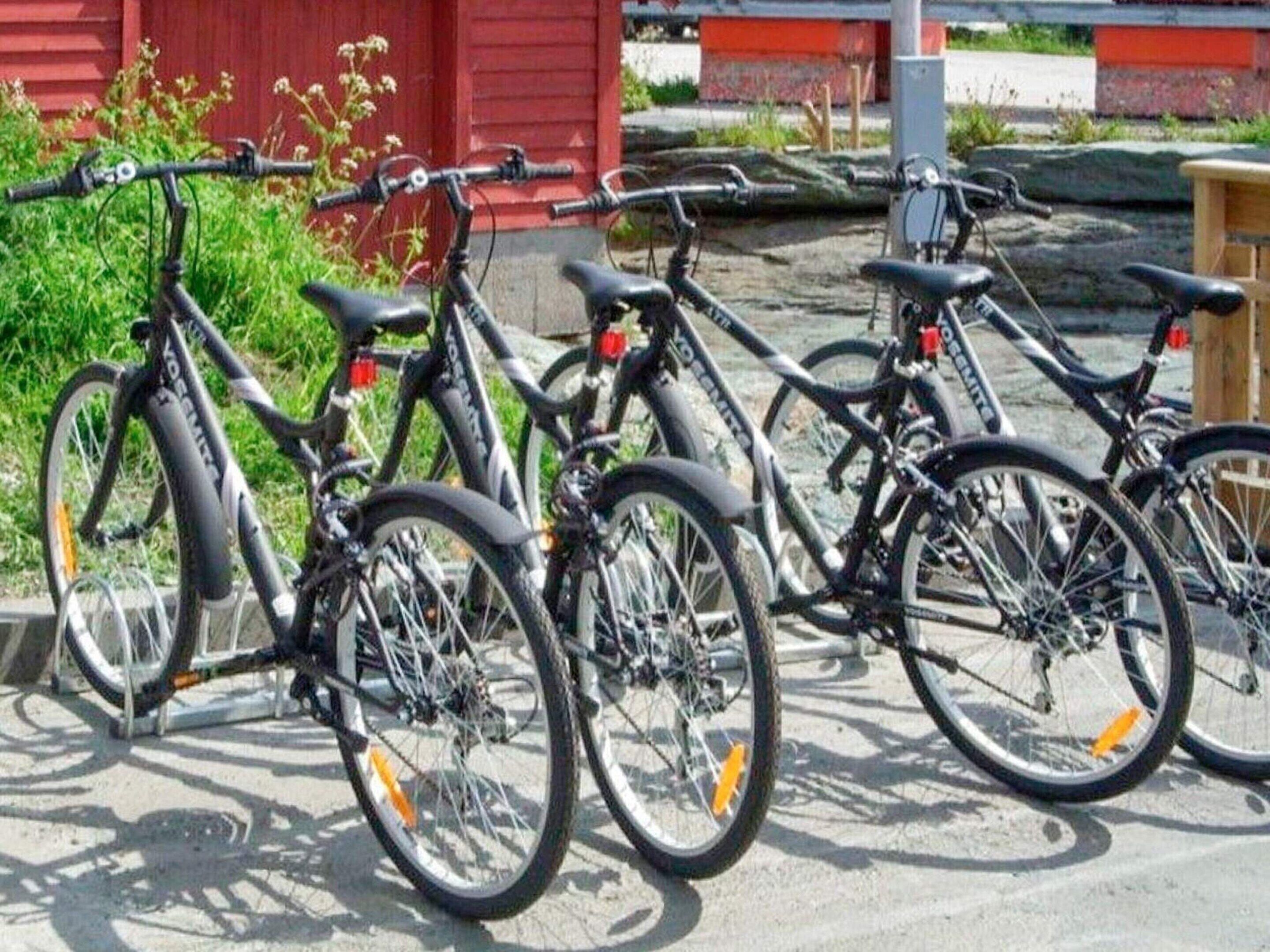 Une rangée de vélos est garée devant un bâtiment rouge.