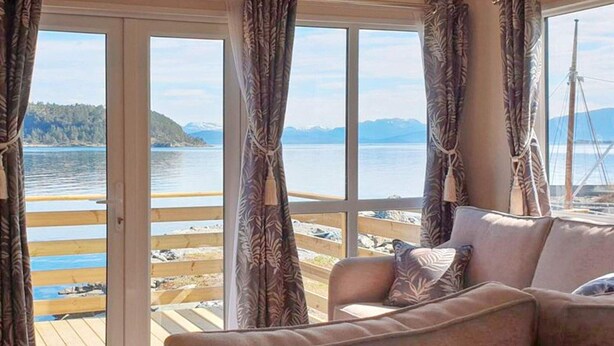 Una habitación con un sofá frente a un ventanal grande que da a un muelle y al agua.