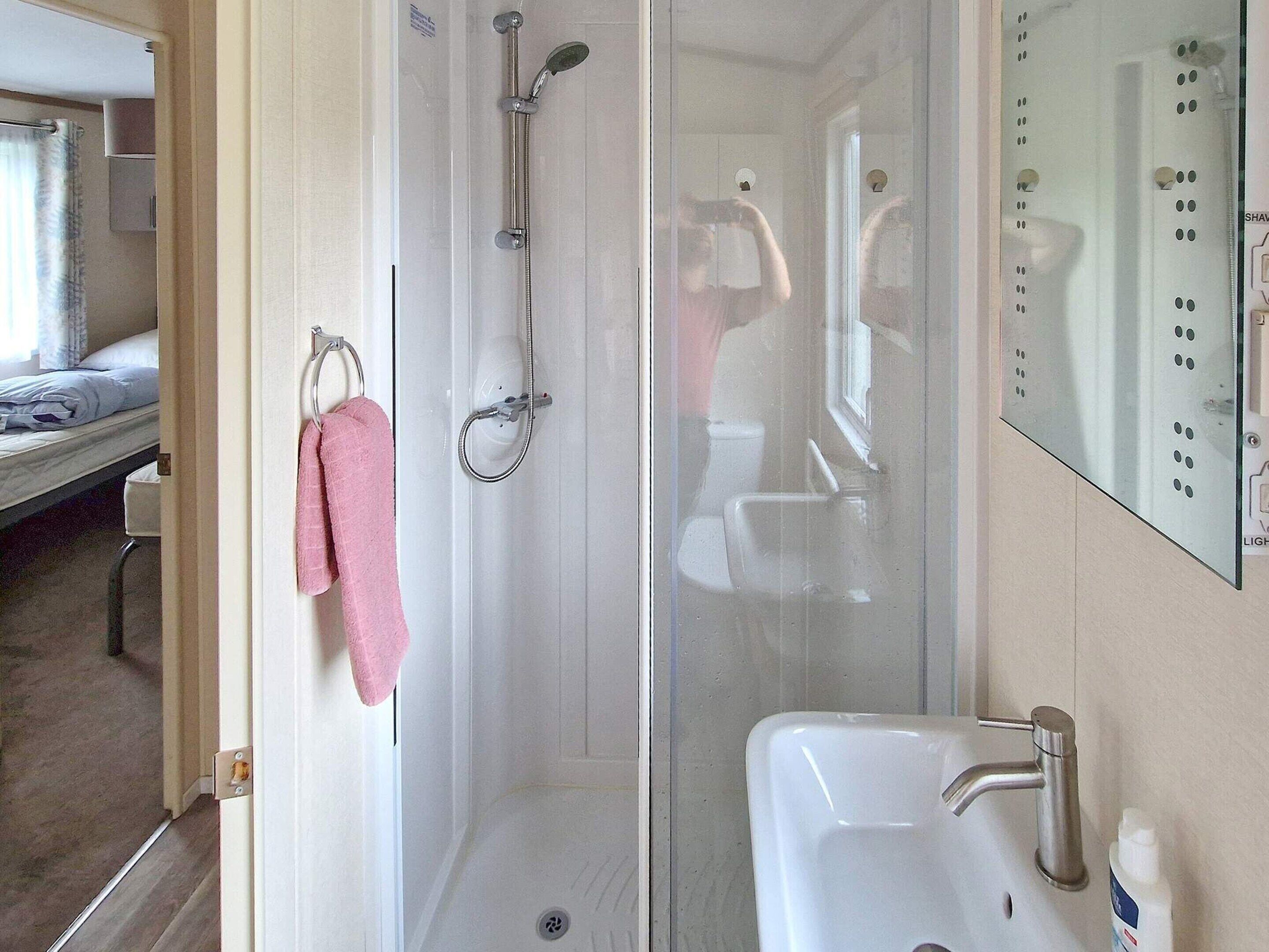 Un bagno con doccia, lavandino e specchio.