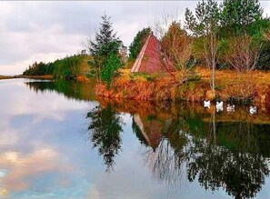 A serene lakeside scene with a house and trees reflecting on the water. - 6 Person Holiday Home in Tansoy (Kinn)
