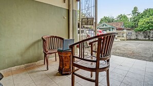 Un espace extérieur abrité comprenant deux chaises en bois et un ordinateur portable posé sur une petite table.